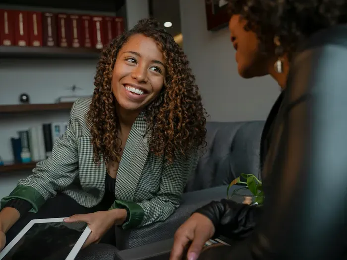 Smiling consultant with a client on a sofa and tablet, showing how CityBiz Now connects people with local advisors